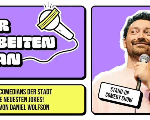 Ein lachender Berliner Comedian hält ein Mikrofon. Daneben steht "Wir arbeiten dran" und "Stand-Up Comedy Show".