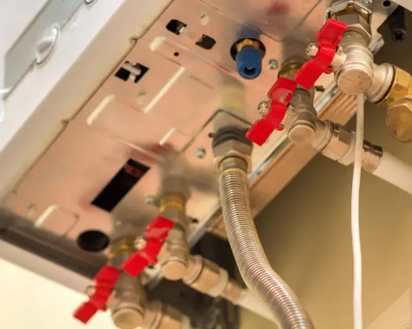Dettaglio di una caldaia con valvole rosse e tubi. Monitorare la pressione massima caldaia è fondamentale per la sicurezza.