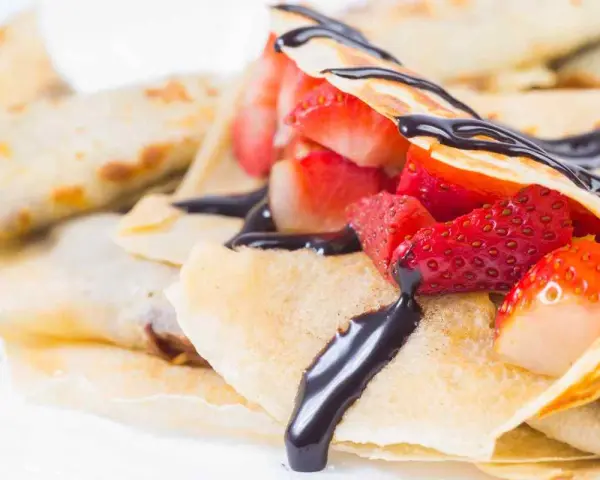 Deliziose crepes senza burro, ripiene di fragole fresche e ricoperte da una golosa salsa al cioccolato.