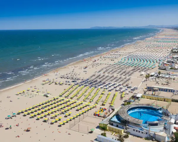 Słoneczna plaża w Rimini, pełna leżaków i parasoli, zaprasza na wakacje. Idealne miejsce na loty do Rimini!