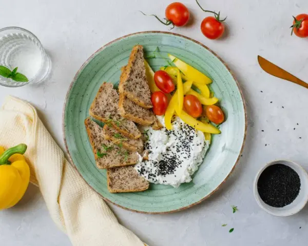 Talerz z twarogiem, pieczywem, pomidorkami i papryką. Idealne na śniadanie z serii dieta wysokobiałkowa przepisy.