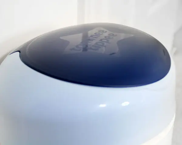 Niebieska pokrywa kosza na pampersy Tommee Tippee z wygrawerowanym logo.