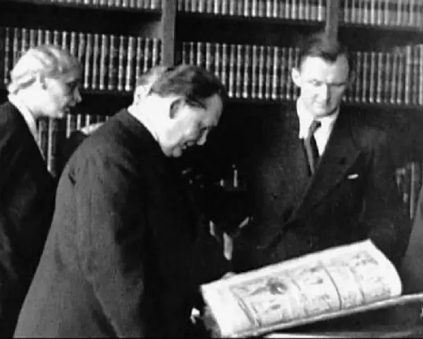 Bruno Lohse et d'autres hommes examinant un livre ouvert dans une bibliothèque.