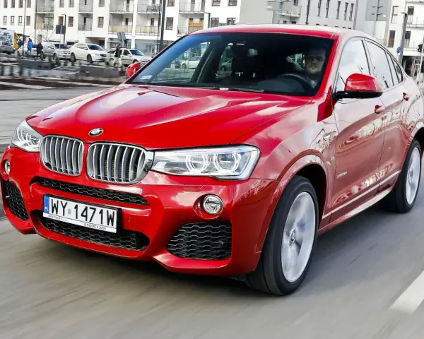 Czerwone BMW X4 w ruchu miejskim. Wady tego modelu mogą dotyczyć widoczności z tyłu i ograniczonej przestrzeni bagażowej.