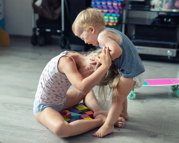 Kleinkind hält älteres Kind am Kopf fest. Was tun, wenn Kinder schlagen? Hier wird spielerisch gestritten.