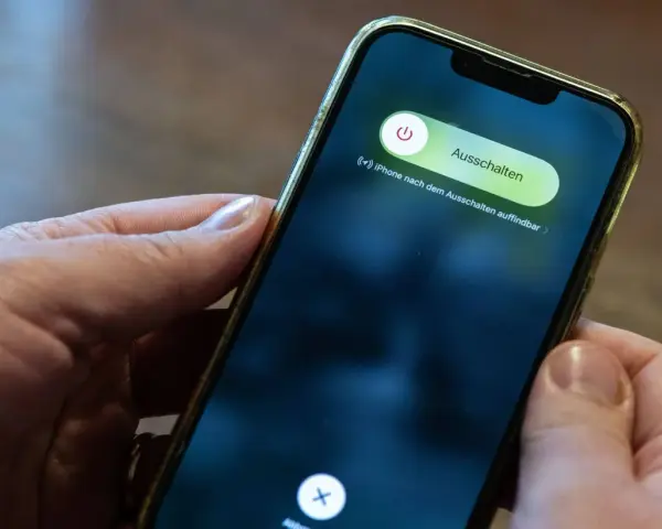 Hände halten ein iPhone mit dem Ausschaltmenü.