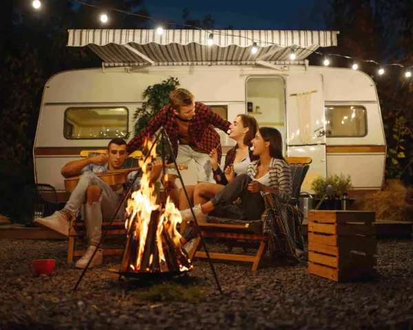 Freunde genießen einen gemütlichen Abend bei Lagerfeuer und Gitarrenmusik während ihres Campingurlaubs in Deutschland.