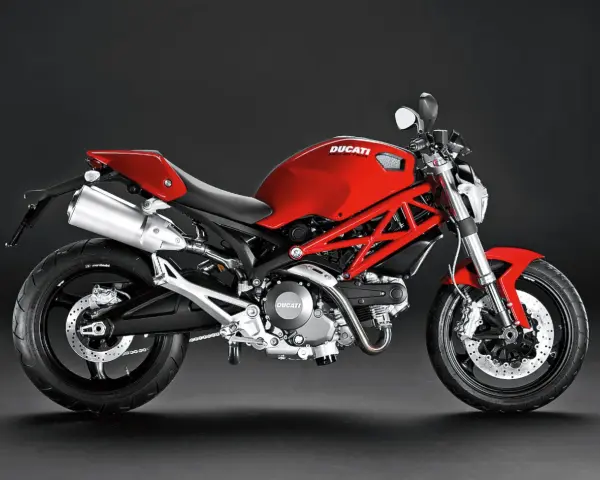 Czerwony Ducati Monster 696 z charakterystyczną kratownicową ramą, błyszczącym wydechem i sportowym siedzeniem.