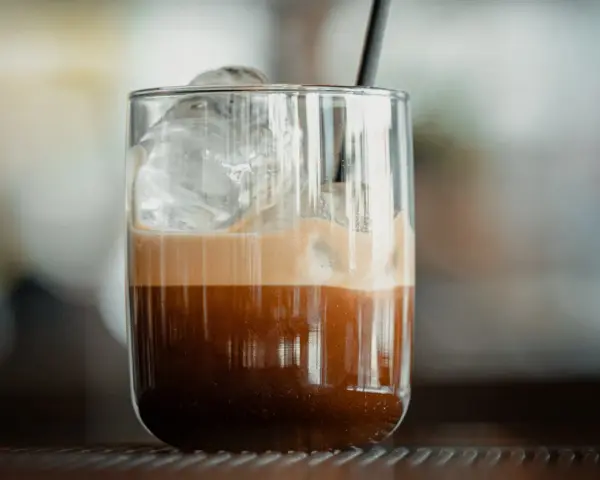 Orzeźwiające freddo espresso z lodem i pianką w szklance, gotowe do wypicia.