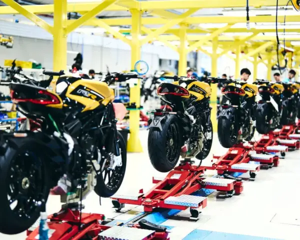 Linea di produzione MV Agusta: moto sportive gialle e nere in fase di assemblaggio su supporti rossi.
