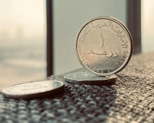 Monety z Zjednoczonych Emiratów Arabskich. Jedna z nich, z napisem "United Arab Emirates", stoi pionowo. To właśnie te monety symbolizują walutę AED, co to jest?