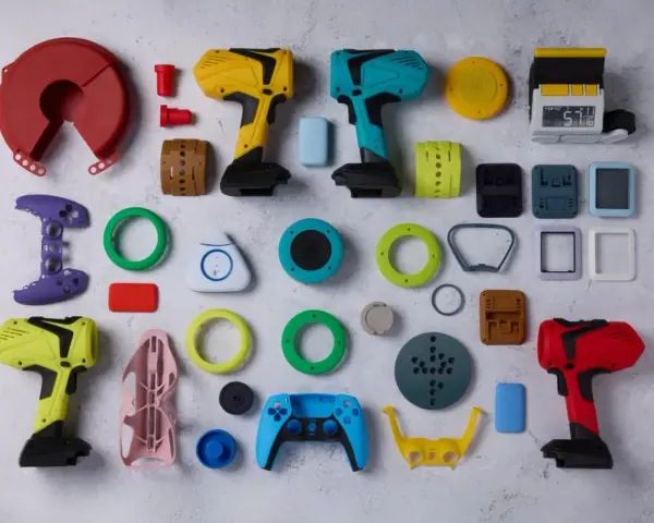 A vibrant collection of components, likely from a color resin 3D printer project, including tool-like objects, game controller parts, and various geometric shapes.