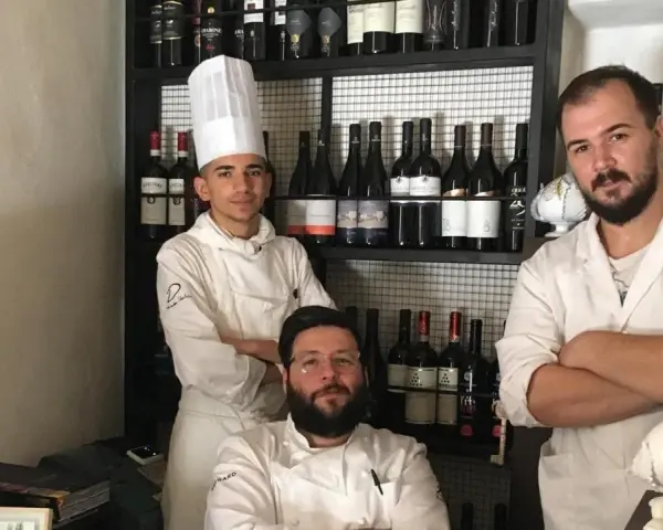 Tre chef posano davanti a una cantina di vini in un ristorante stellato Puglia.