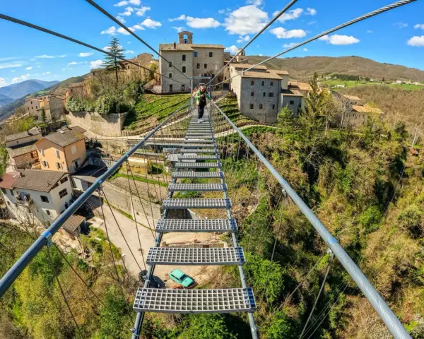 Ponte tibetano sellano, una passerella sospesa che collega borghi antichi, offre una vista mozzafiato sulla valle. La sua lunghezza è un'avventura.