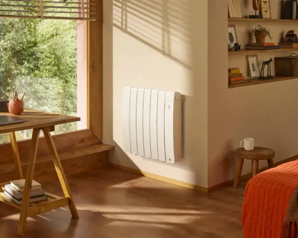 Radiateur blanc mural, discret et efficace, diffusant une chaleur douce grâce à son fluide caloporteur. Un coin bureau et un lit douillet complètent cette pièce chaleureuse.