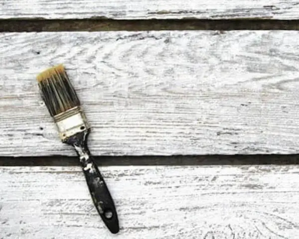 Pennello sporco su assi di legno bianco, pronto per la cementite per legno già verniciato.