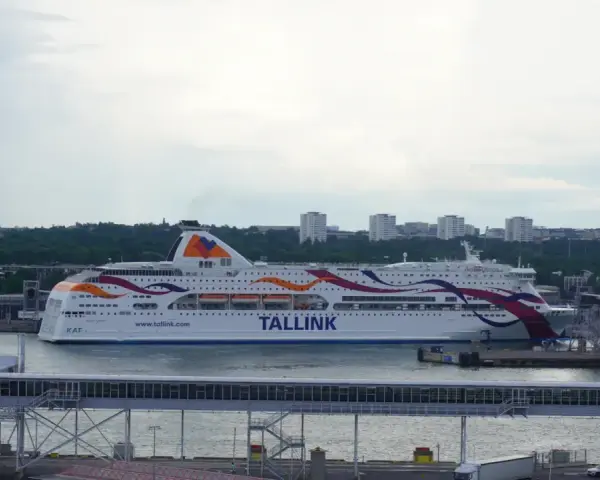 Prom Tallink płynie z Tallinna do Sztokholmu. Statek z kolorowymi pasami na burcie cumuje w porcie.