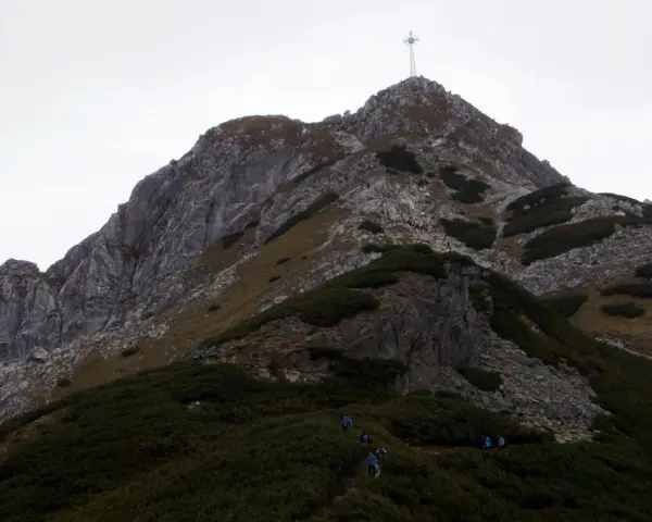 Wspinaczka na Giewont. Grupa turystów pokonuje skaliste zbocze, gdzie w trudniejszych miejscach pomagają łańcuchy.