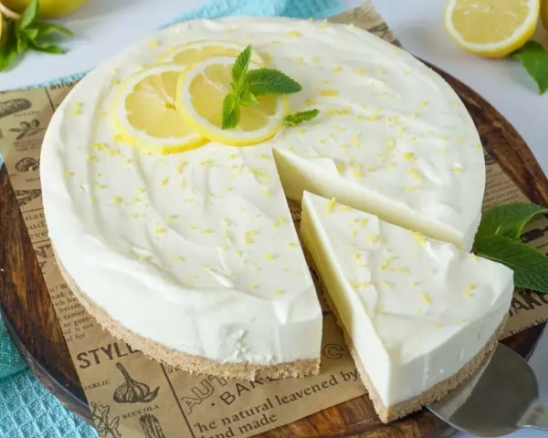 Cremige Philadelphia Torte mit Zitronenscheiben und Minze, ein Stück wurde bereits entnommen.