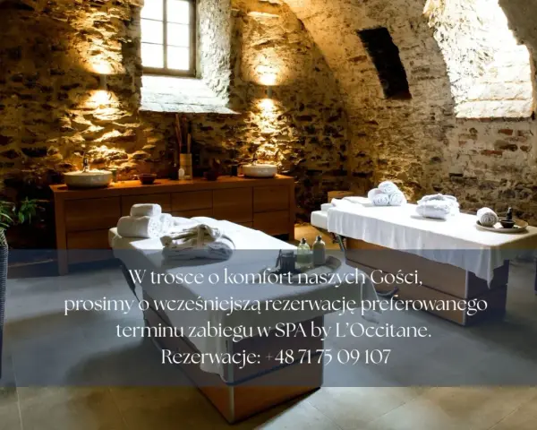 Przytulne wnętrze SPA koło Wrocławia z dwoma stołami do masażu, kamiennymi ścianami i relaksującym oświetleniem.