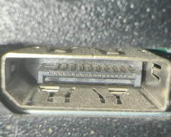 Närbild på ett dammigt displayport uttag med synliga kontakter och fästen.