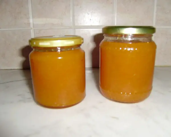 Due barattoli di marmellata di pesche fatti in casa, pronti per essere gustati.