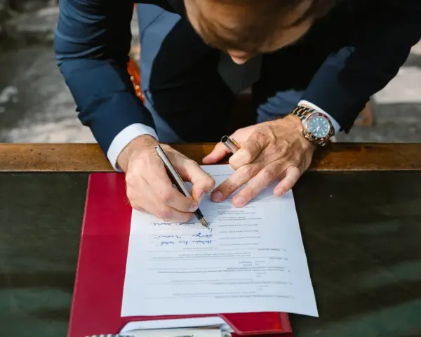 Mężczyzna w garniturze podpisuje dokument. Zastanawia się, jakim nazwiskiem podpisać się na ślubie cywilnym, wybierając to właściwe.