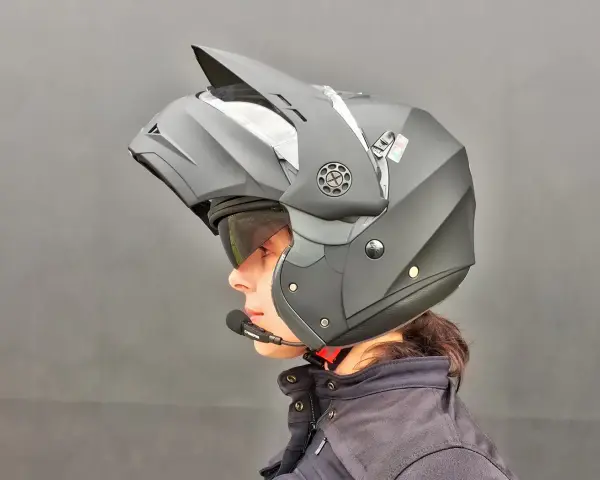 Profilo di una persona con casco da moto modulare nero, visiera sollevata e microfono. Guida sicura: come scegliere casco moto.