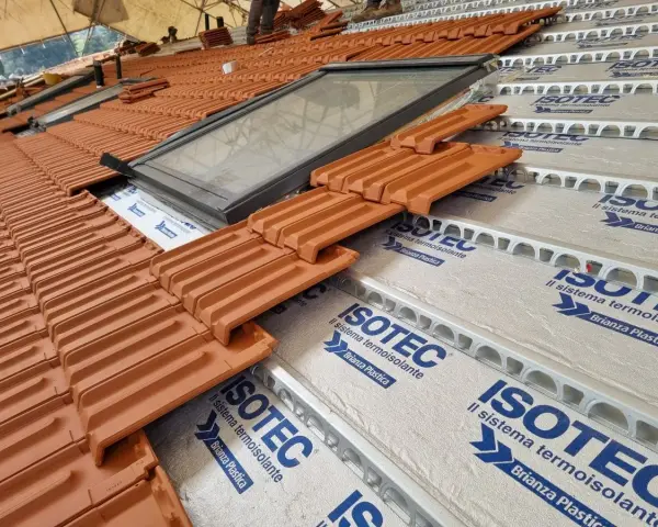 Tegole in laterizio su un tetto in costruzione, con lucernario e isolamento termoisolante ISOTEC.