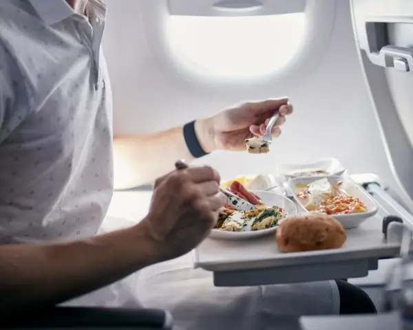 Pasażer je posiłek na pokładzie samolotu. Zastanawiasz się, czy można przewozić jedzenie w bagażu rejestrowanym Ryanair?