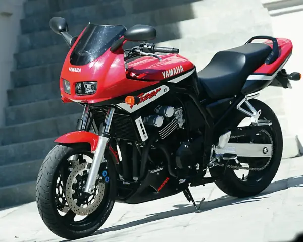 Czerwony motocykl Yamaha FZ6 z czarnym siedzeniem i owiewką, zaparkowany na zewnątrz.