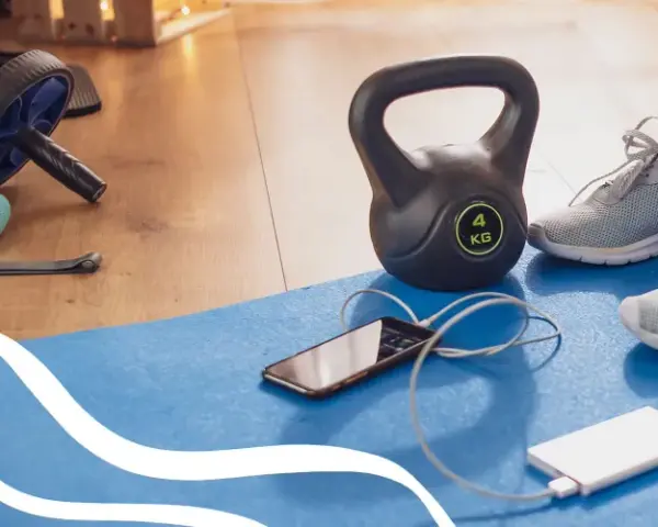 Gotowy na trening cardio? Kettlebell, gumy oporowe, rolka do ćwiczeń i telefon z powerbankiem czekają na matę.