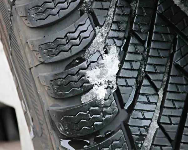 Gomme invernali con neve e ghiaccio incastrati nel battistrada. Le gomme screpolate battistrada mostrano segni di usura, ma ancora funzionali.