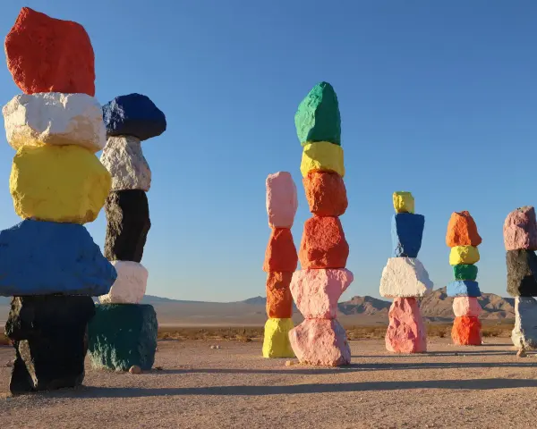 Les **seven magic mountains** illuminent le désert. Des rochers colorés empilés créent une œuvre d'art vibrante sous un ciel bleu.