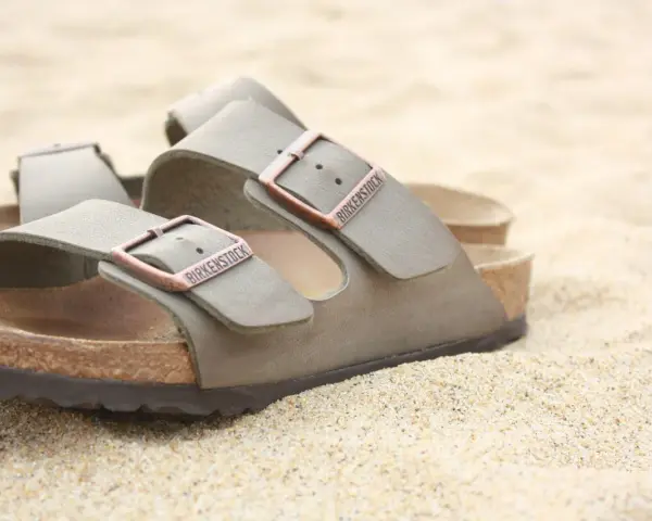 Sandali Birkenstock grigi sulla sabbia. Scopri come si lavano le Birkenstock per mantenerle perfette.