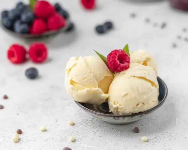 Cremiges Vanilleeis, garniert mit einer Himbeere. Perfekt, um eis ohne zucker selber machen zu lernen.