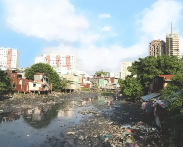 Un río lleno de basura y aguas residuales, rodeado de casas precarias y edificios modernos, ilustra los graves tipos de contaminación que afectan a esta comunidad.