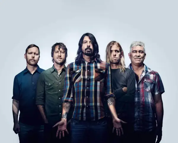Les membres de Foo Fighters posent ensemble, cinq hommes aux regards intenses, prêts à enflammer la scène.