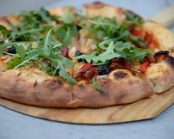 Pyszna pizza z rukolą i oliwkami, idealna na szybki przepis na ciasto do pizzy.