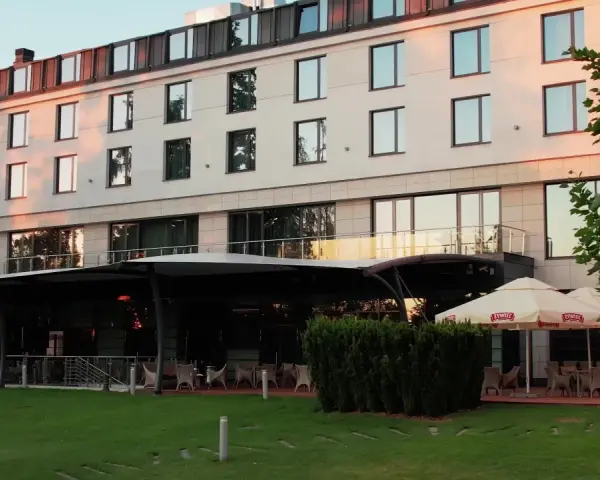 Nowoczesny hotel z tarasem i ogródkiem, gdzie można usiąść. Czy to jeden z hoteli Hilton w Warszawie?