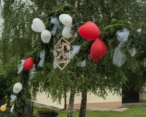 Brama weselna z balonami i napisem "Witamy Parę Młodą". Tradycja bram weselnych to symboliczne powitanie nowożeńców przez gości.