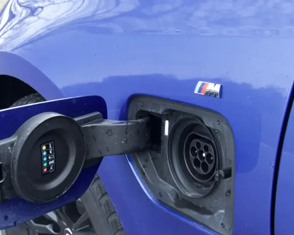 Niebieskie BMW 330e z otwartą klapką gniazda ładowania.