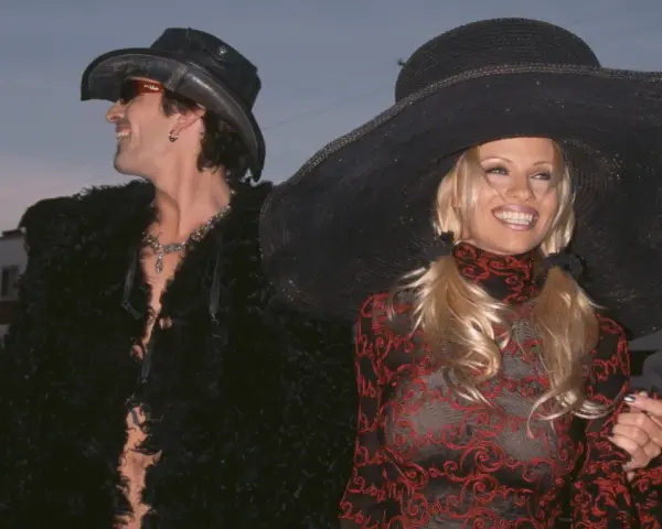 Pamela Anderson i Tommy Lee w stylizacjach z epoki. Ona w wielkim kapeluszu i wzorzystej sukience, on w kowbojskim kapeluszu i futrzanej kurtce.