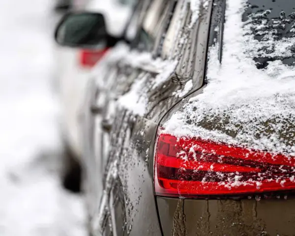 En mörk bil täckt av snö och is. En perfekt dag för ett bilvårdspaket för att få bilen skinande ren igen.