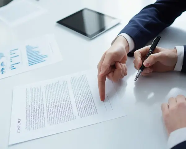 Biznesmen wskazuje palcem na dokument "CONTRACT", przygotowując się do podpisania umowy b2b.