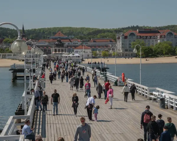 Spacer po molo w Sopocie, gdzie tłumy ludzi korzystają z uroków Bałtyku. To idealne miejsce na relaks i odkrywanie gdańskich atrakcji dla dorosłych.
