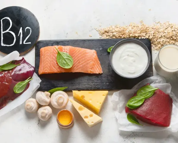 W czym jest witamina B12? Na talerzu wątróbka, łosoś, wołowina, krewetki, sardynki, ser, jajko, jogurt, mleko, płatki owsiane i kapsułki.