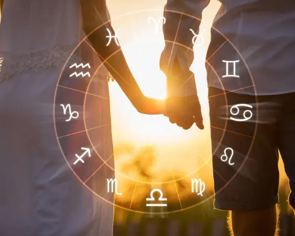 Para zakochanych trzymających się za ręce na tle zachodzącego słońca, z nałożonym kołem zodiaku. 11 czerwiec znak zodiaku to Bliźnięta.