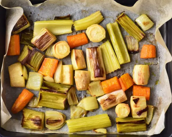 Pokrojone w kawałki marchewki, por i seler przygotowane do pieczenia. Idealne do aromatycznego rosół z pieczonych warzyw.