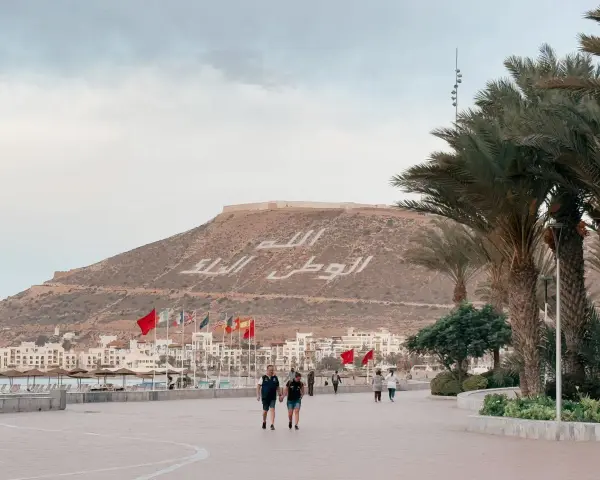Spacerem po promenadzie w Agadirze, z widokiem na miasto i napisem na wzgórzu. Czy Agadir jest bezpieczny? Tak, wygląda na spokojne miejsce.